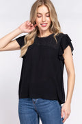 Woman wearing a black top with lace details and blue jeans on a white background