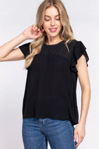Woman wearing a black top with lace details and blue jeans on a white background