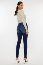Woman wearing a beige top and blue jeans on a white background