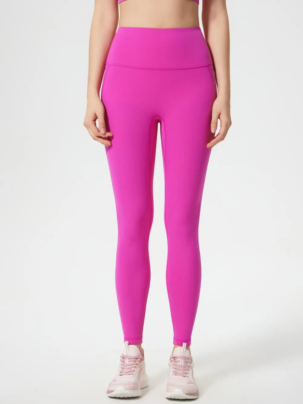Person wearing bright pink leggings on a white background