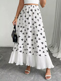 Person wearing a white skirt with black floral patterns on a gray floor.