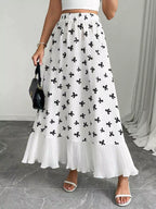 Person wearing a white skirt with black floral patterns on a gray floor.