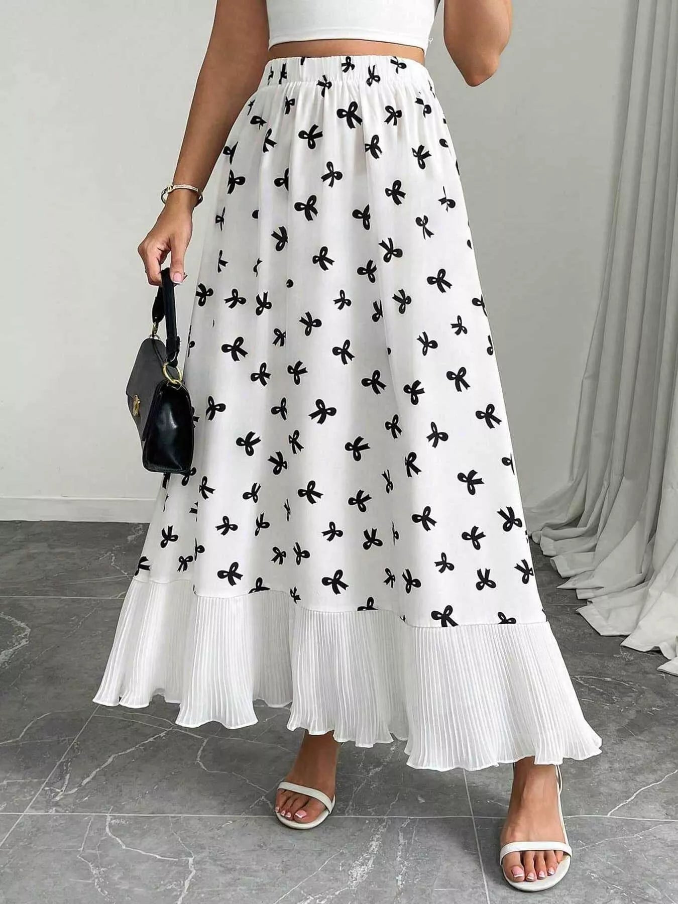 Person wearing a white skirt with black floral patterns on a gray floor.