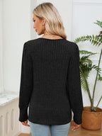 Woman wearing a black sweater in a room with a plant