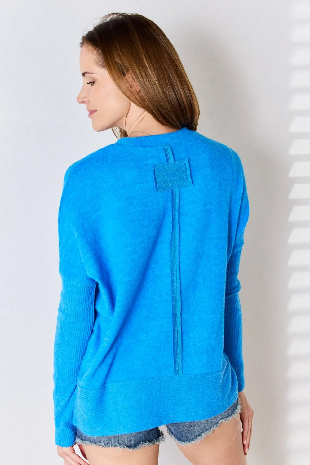 Woman wearing a blue sweater with a pocket on a white background