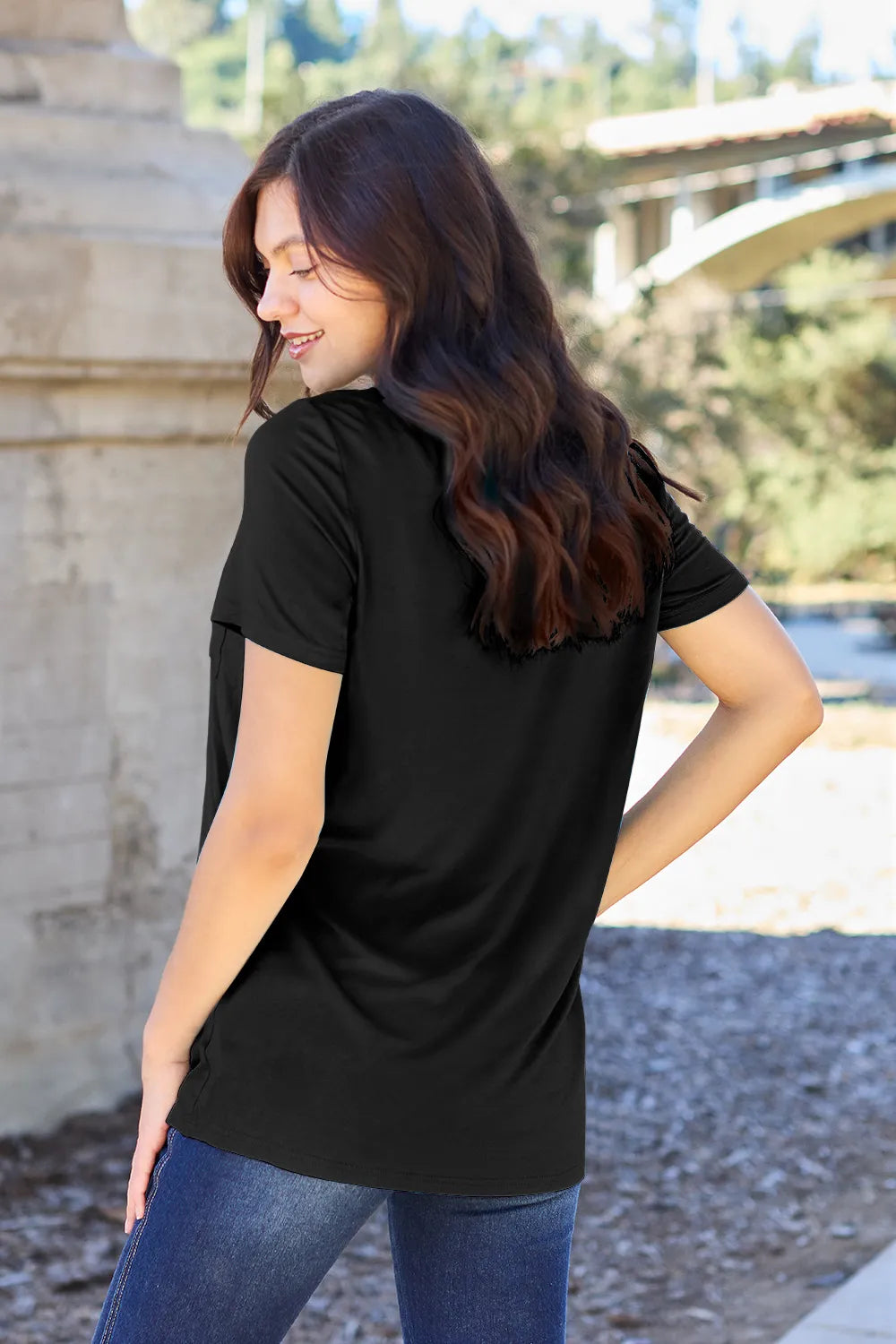Woman wearing a black t-shirt with a blurred outdoor background