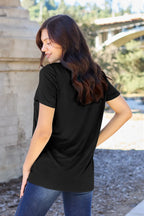 Woman wearing a black t-shirt with a blurred outdoor background