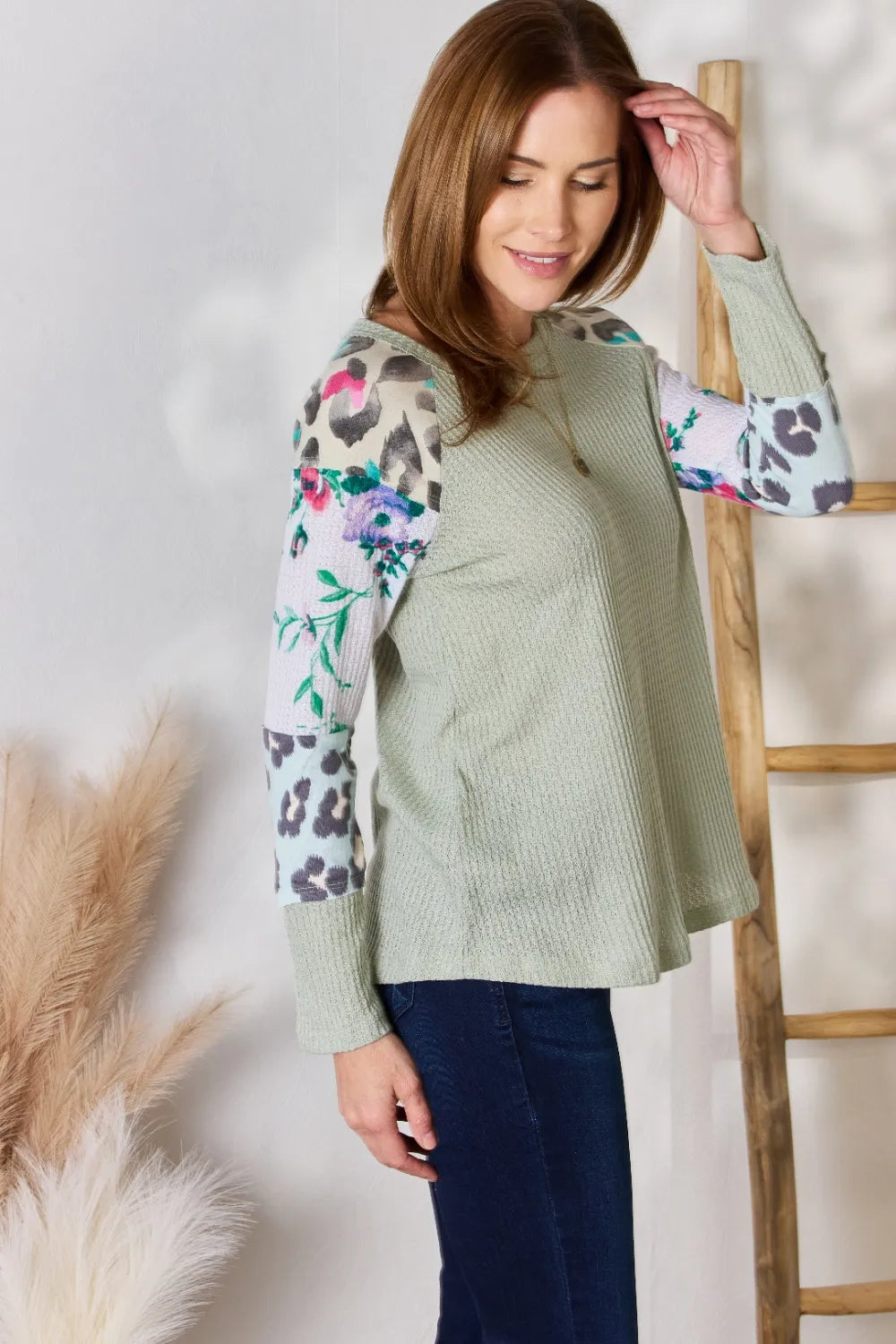 Woman wearing a green sweater with colorful sleeves against a white background