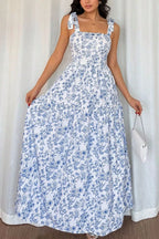 Woman wearing a blue floral dress against a white curtain background