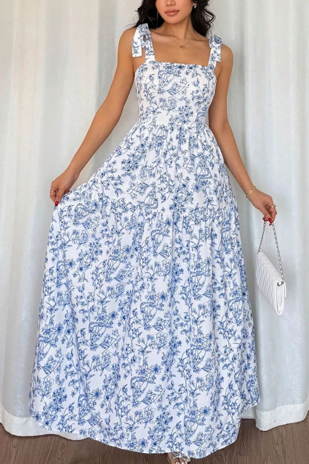 Woman wearing a blue floral dress against a white curtain background