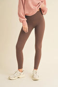 Person wearing gray leggings and a pink sweatshirt on a beige background
