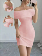 Woman wearing a pink off-shoulder dress with a gray floor and white wall background.