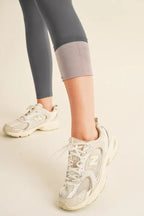 Person wearing light-colored sneakers and gray leggings on a neutral background