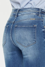Close-up of blue jeans with a visible brand label on a light gray background