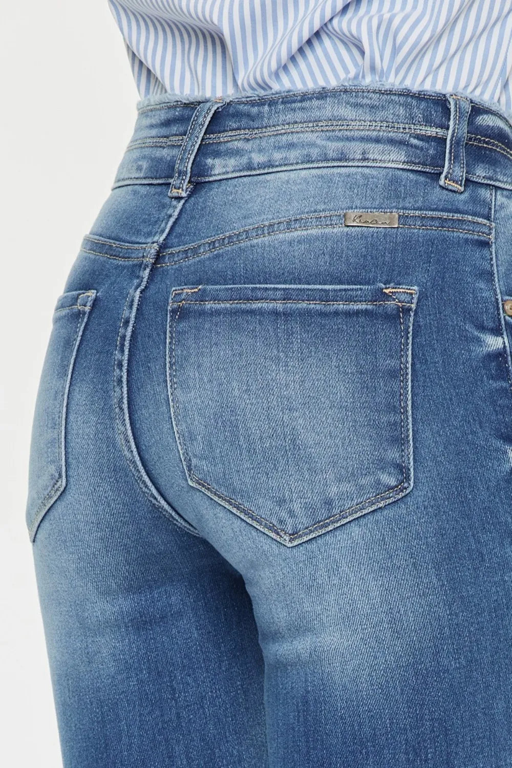 Close-up of blue jeans with a visible brand label on a light gray background