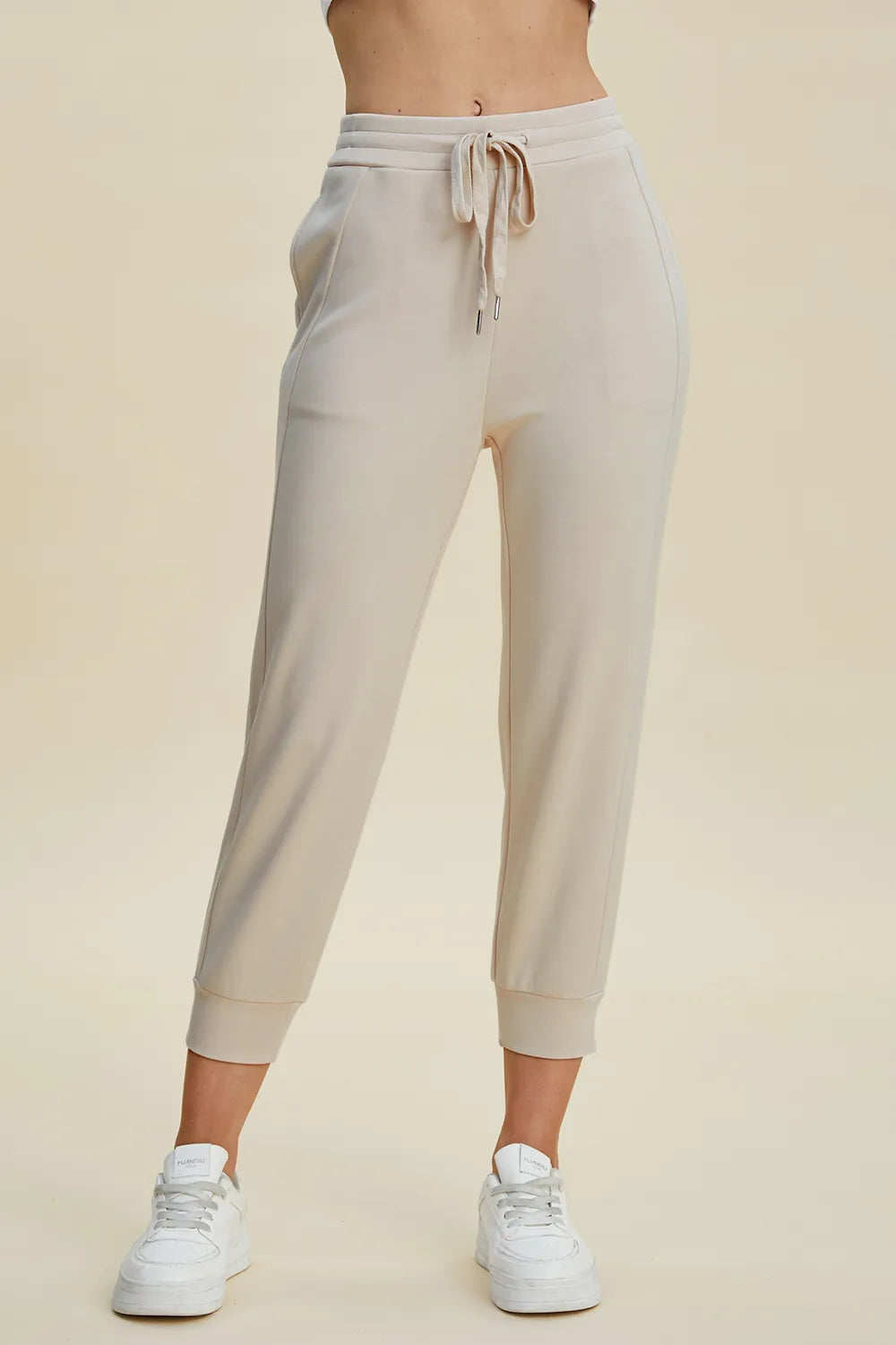 Beige jogger pants worn by a person on a beige background