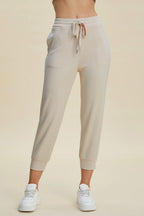 Beige jogger pants worn by a person on a beige background
