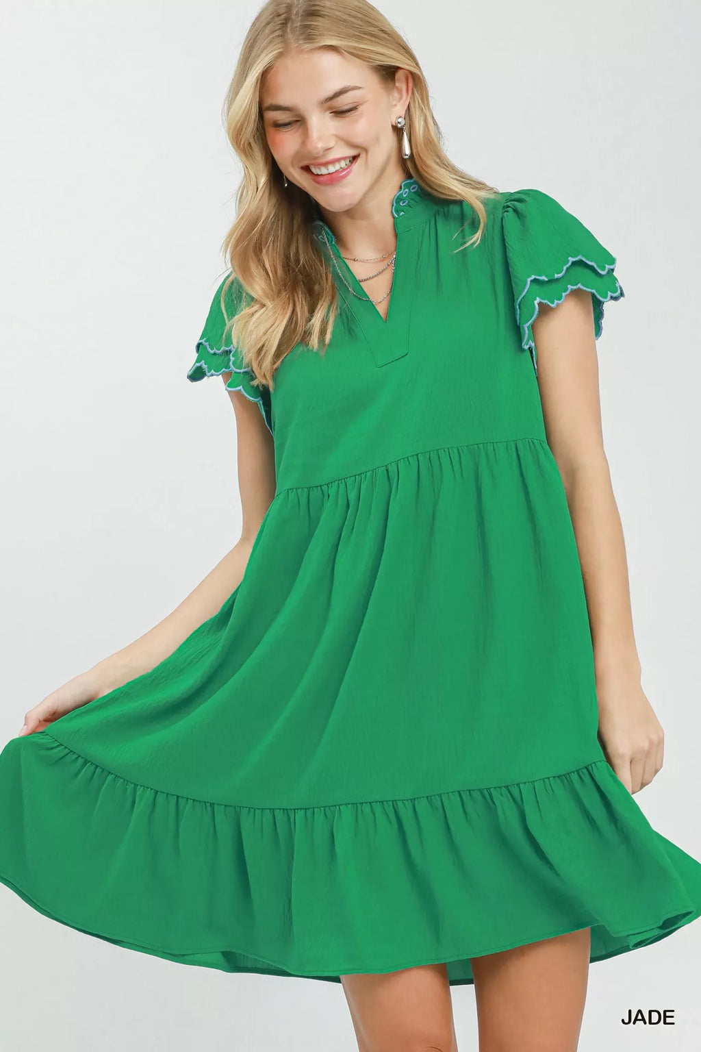 Woman wearing a green dress with ruffled sleeves on a white background