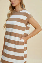 Woman wearing a brown and white striped dress against a beige background