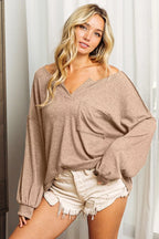 Woman wearing a beige oversized sweater and white shorts indoors.