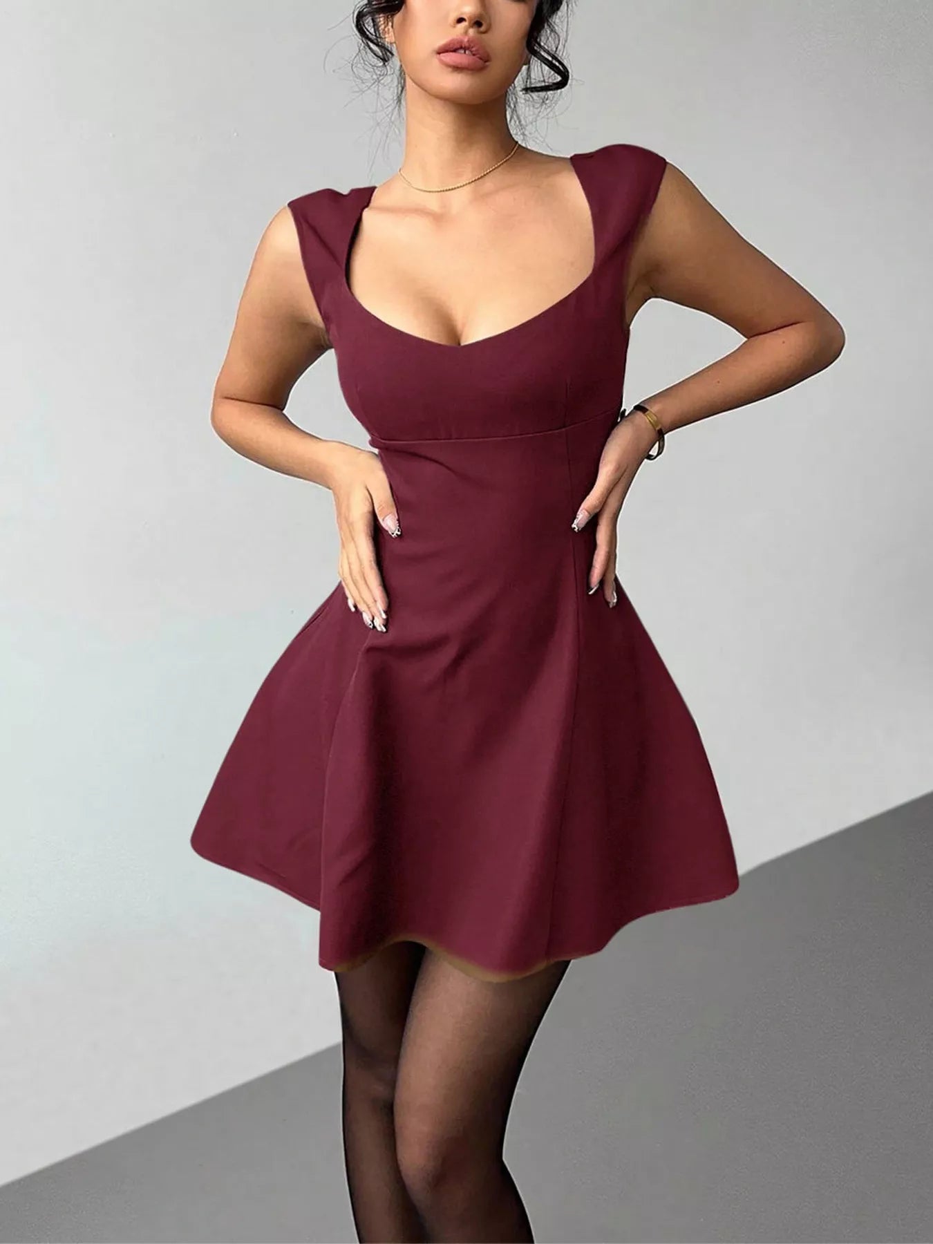 Woman wearing a burgundy dress against a gray background