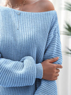 Close-up of a person wearing a blue off-shoulder sweater with blurred background