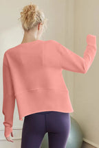 Person wearing a pink sweatshirt and purple leggings in a minimal indoor setting