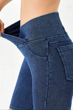 Close-up of blue jeans being pulled up on a person against a white background