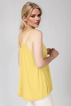Woman wearing a yellow sleeveless top against a plain background