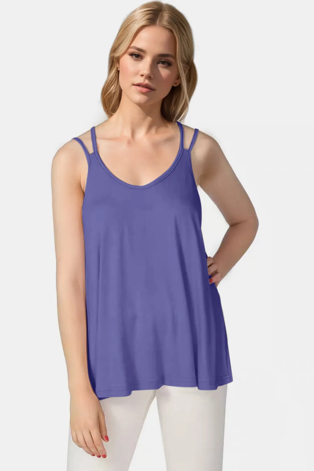 Woman wearing a purple tank top and white pants on a light gray background