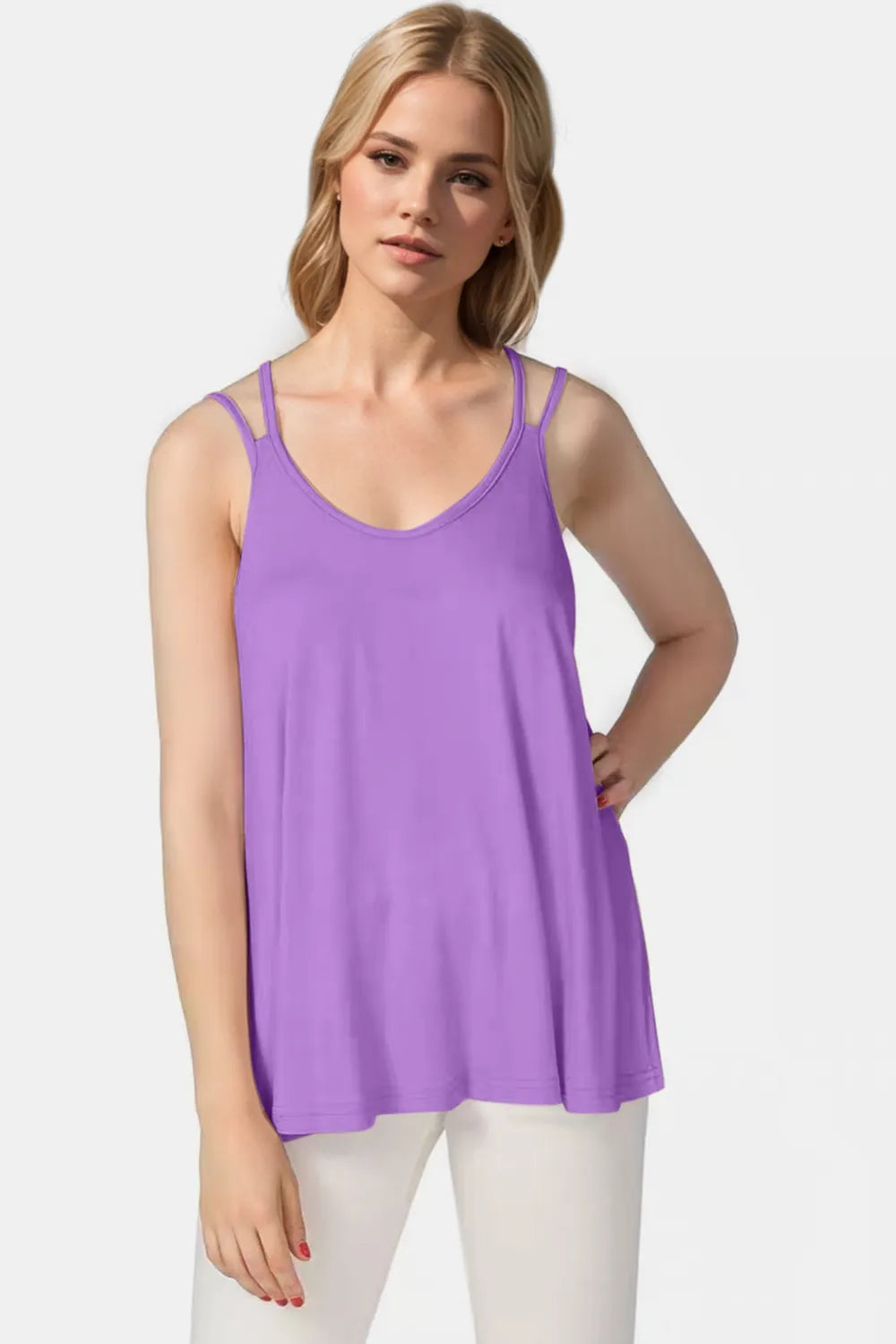 Woman wearing a purple tank top and white pants on a light gray background