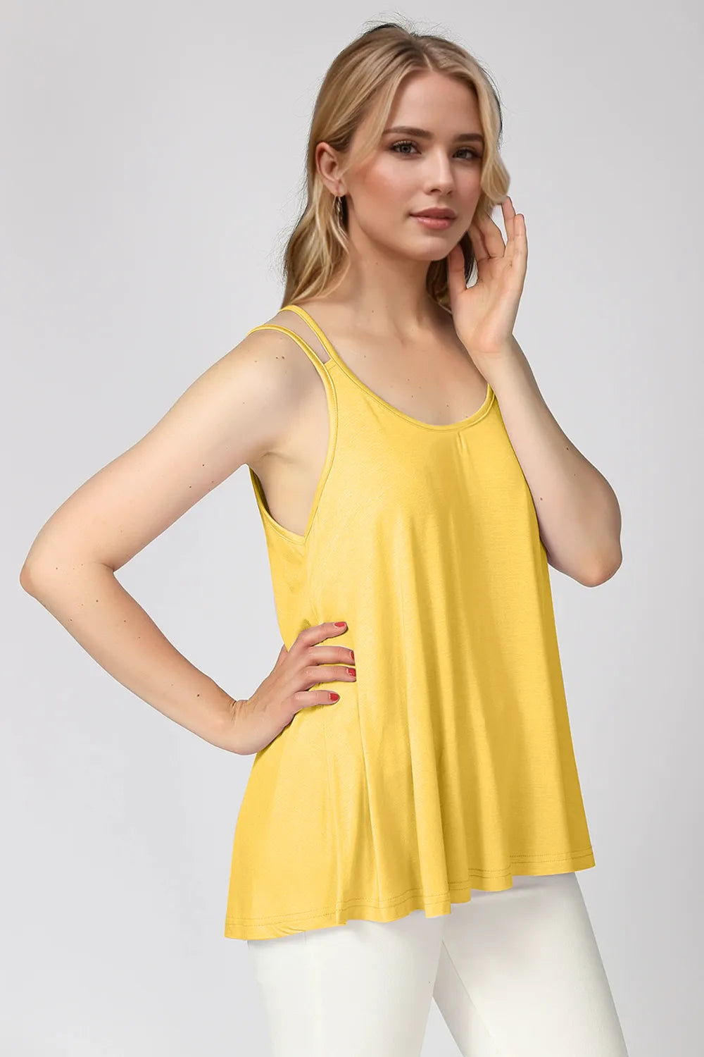 Woman wearing a yellow tank top against a plain background