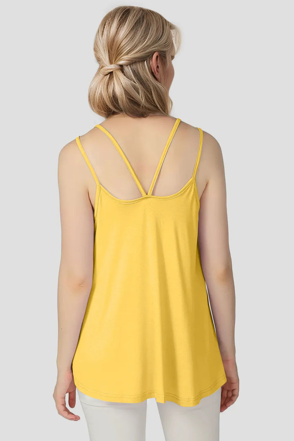 Yellow sleeveless top worn by a person on a plain background