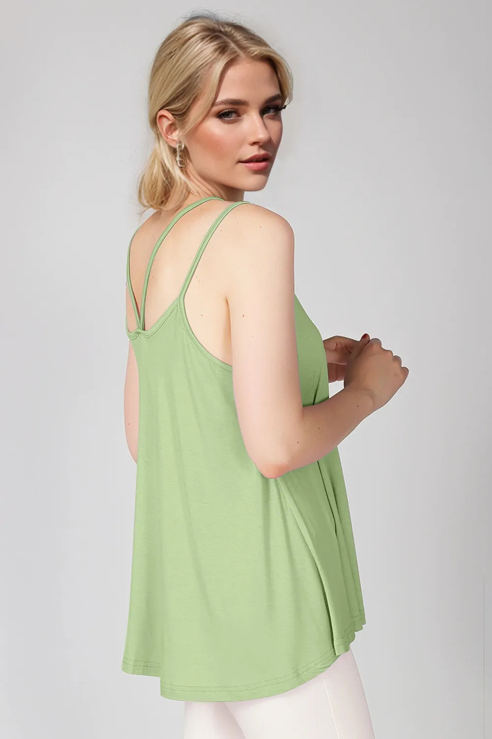Woman wearing a light green tank top on a plain background