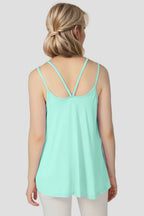 Woman wearing a light green tank top with thin straps on a plain background