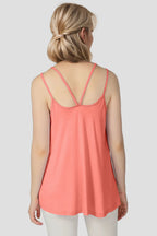Woman wearing a coral tank top with thin straps on a plain background