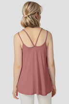 Woman wearing a pink tank top with thin straps on a plain background