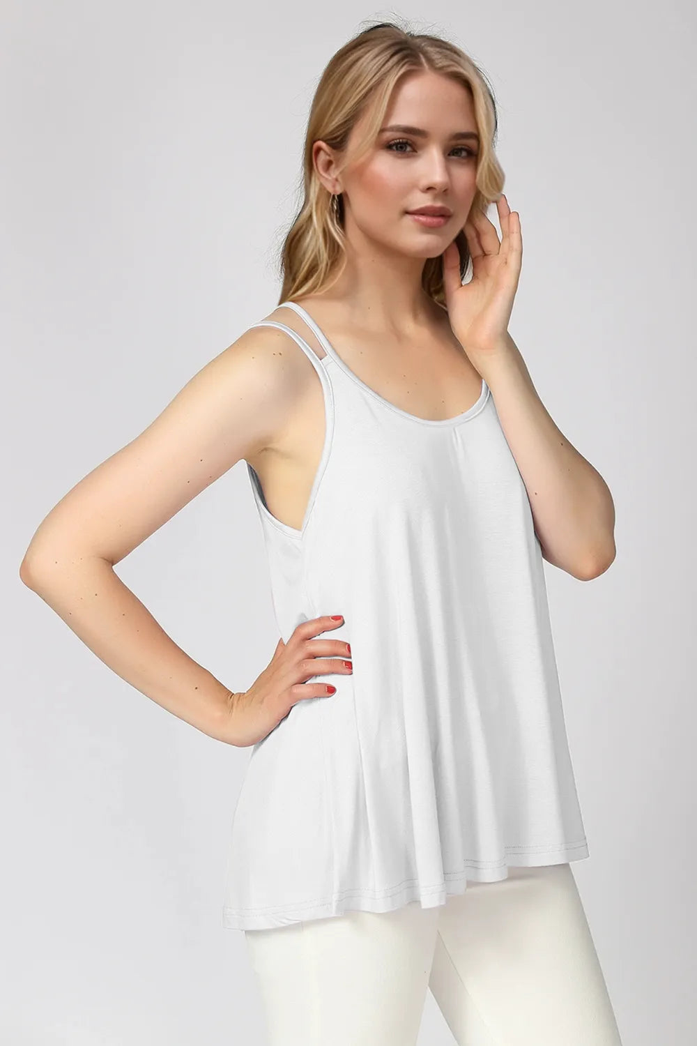 Woman wearing a white sleeveless top against a plain background