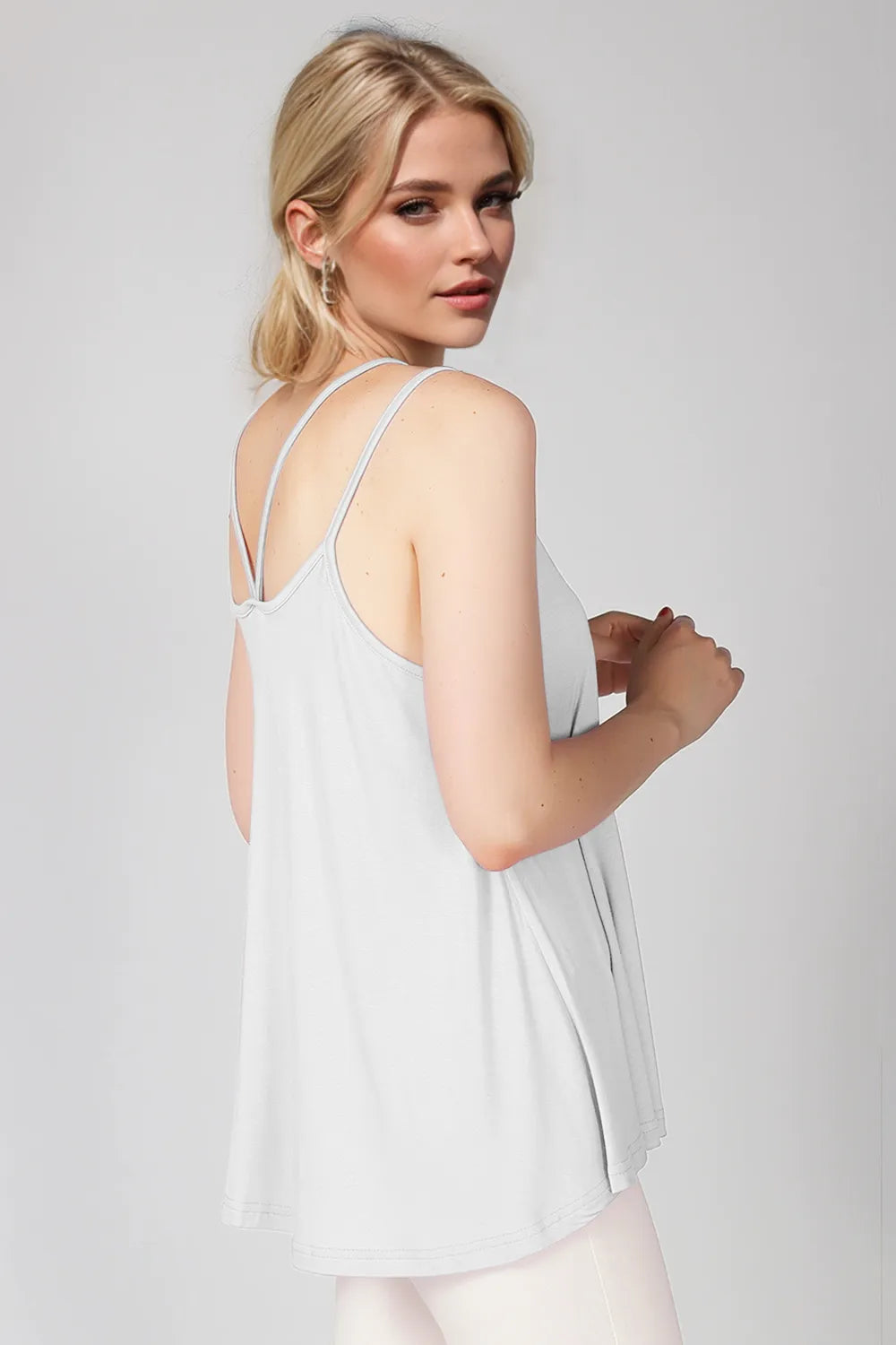 Woman wearing a white sleeveless top against a plain background