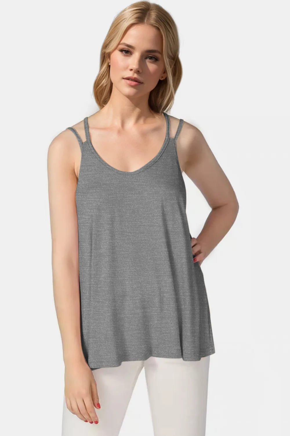 Woman wearing a gray tank top and white pants on a white background
