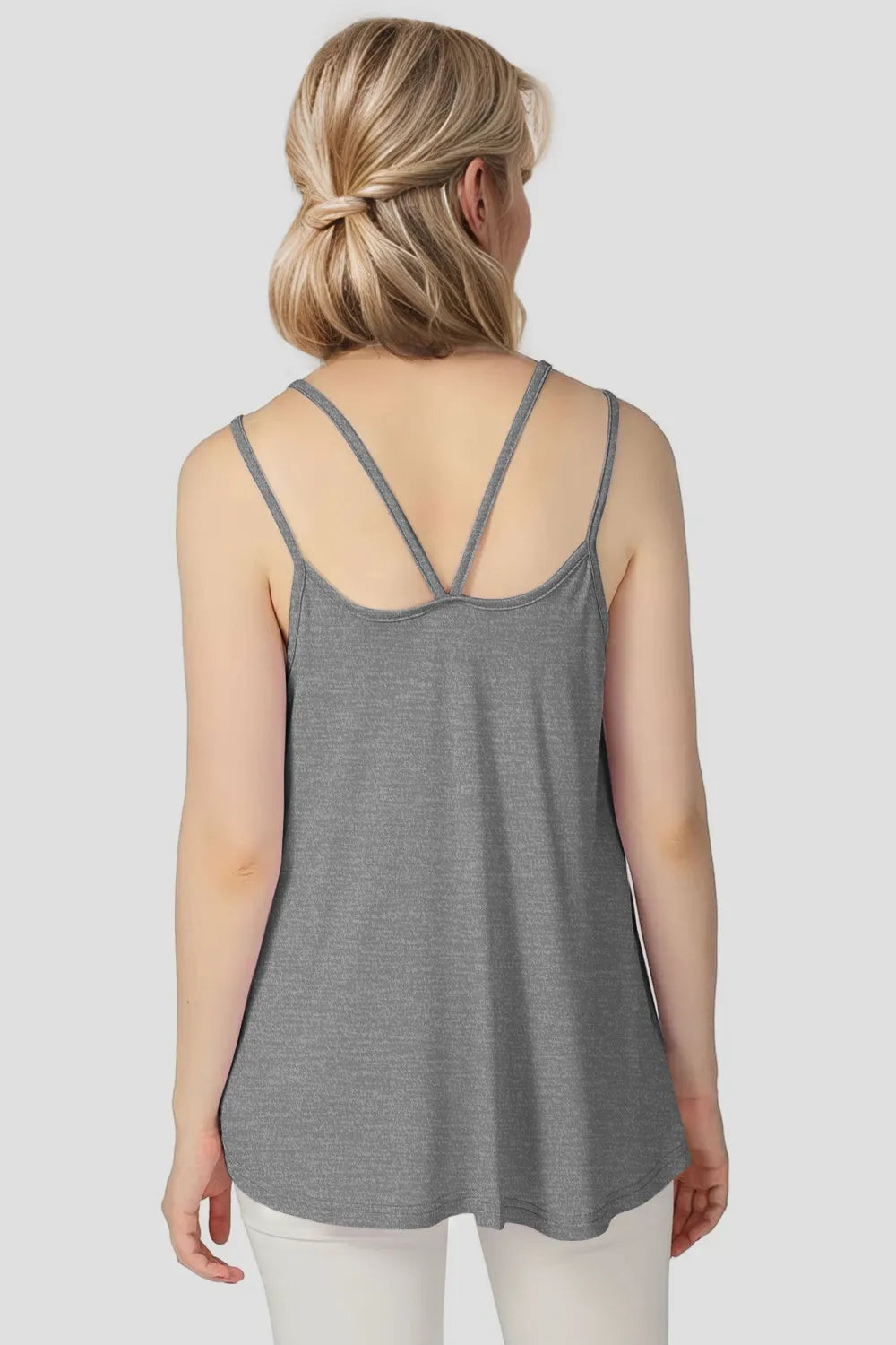 Woman wearing a gray tank top on a plain background