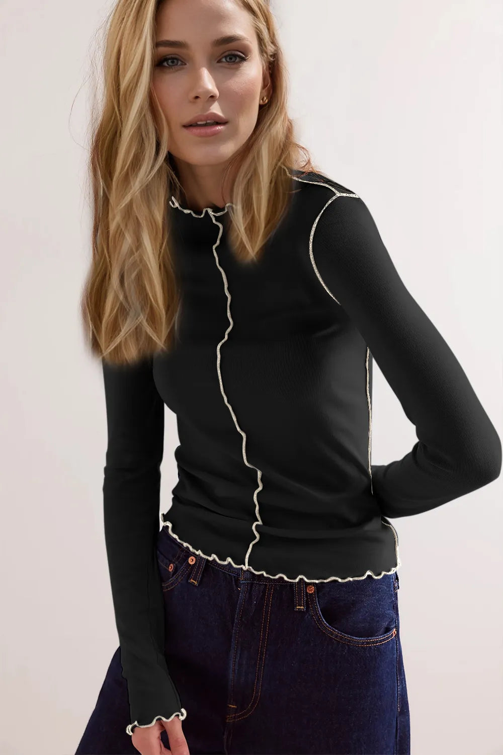 Woman wearing a black long-sleeve top with white trim against a light background