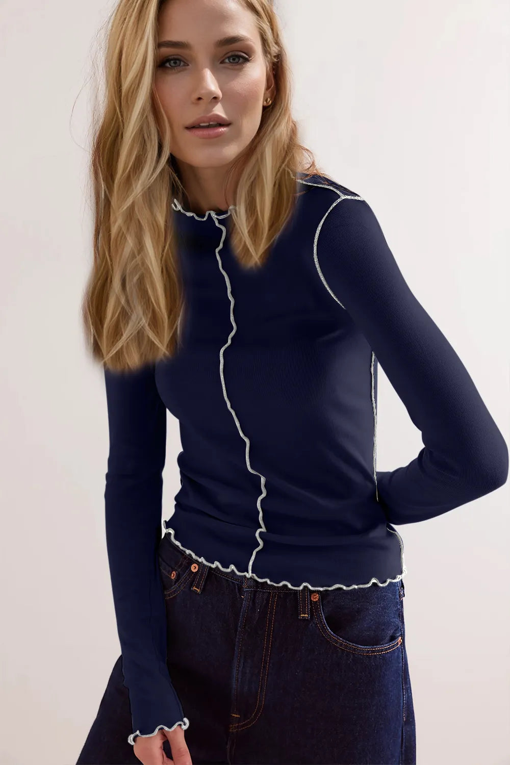 Woman wearing a navy blue long-sleeve top with white trim against a light background