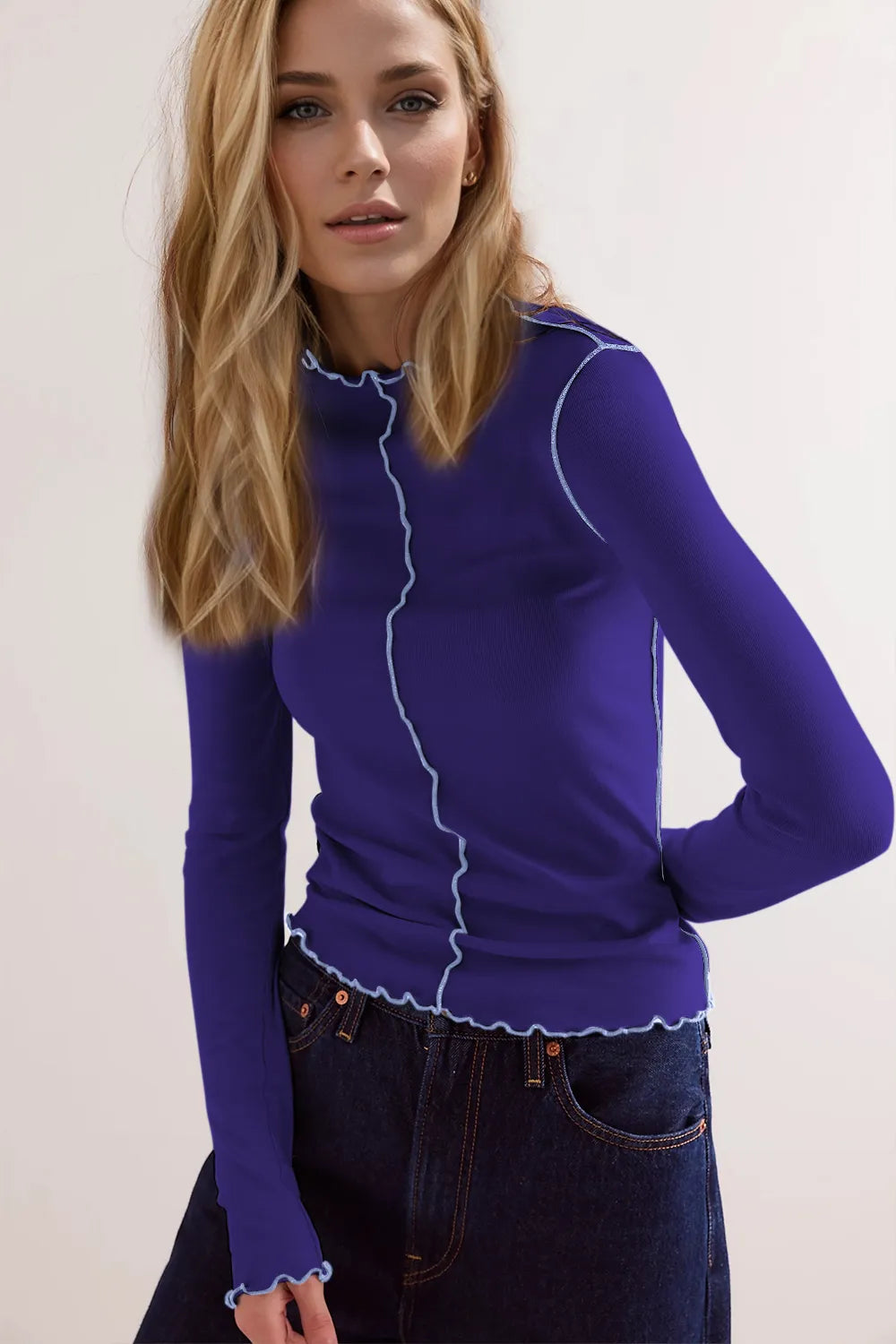Woman wearing a blue long-sleeve top with white trim against a white background