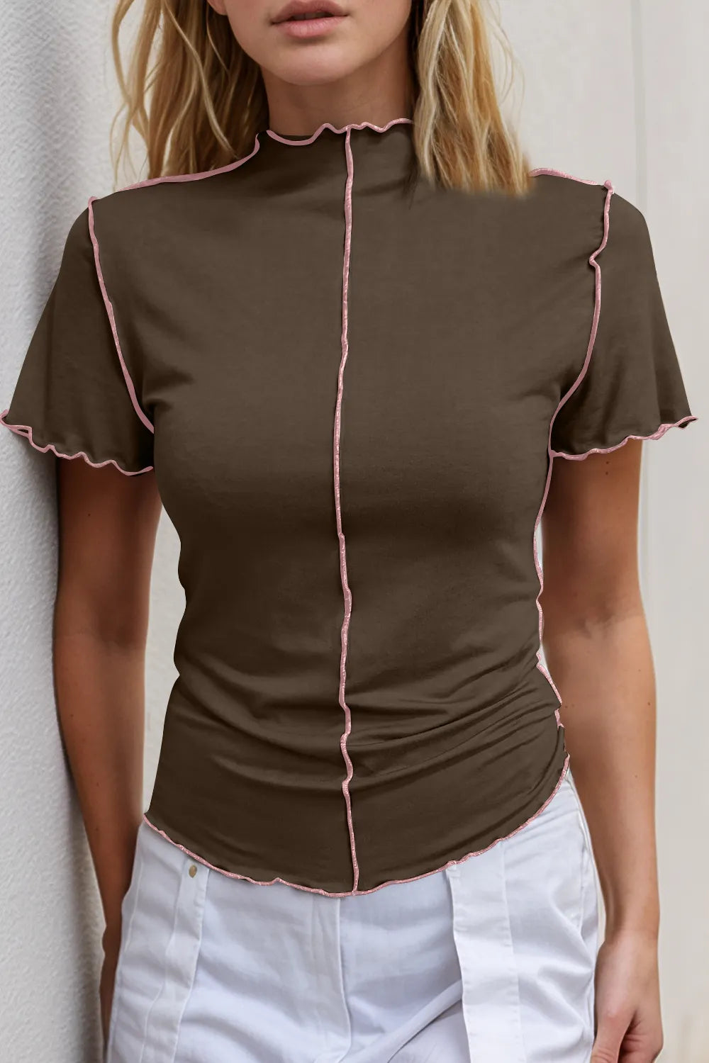 Brown blouse with pink trim worn by a person against a neutral background