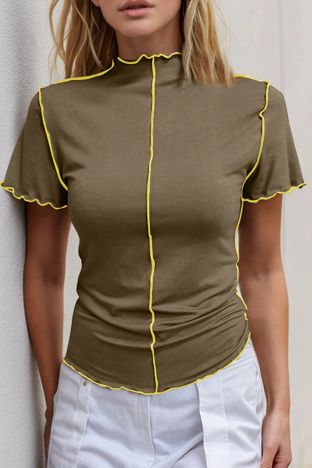 Woman wearing a green blouse with yellow trim against a neutral background