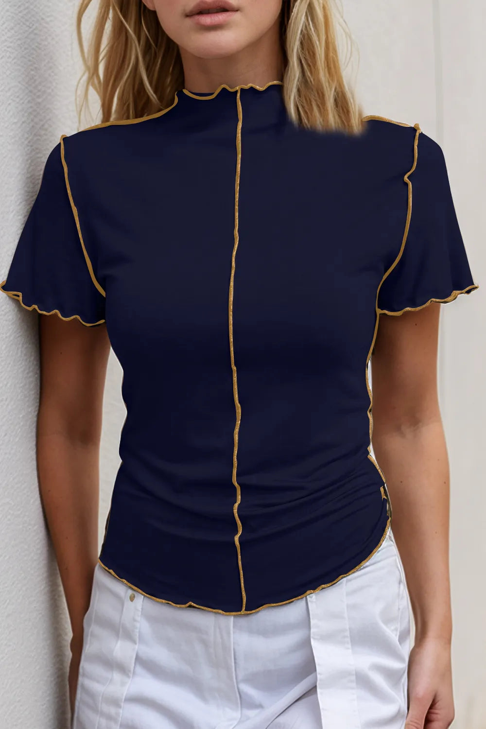 Navy blue top with gold trim worn by a person against a neutral background