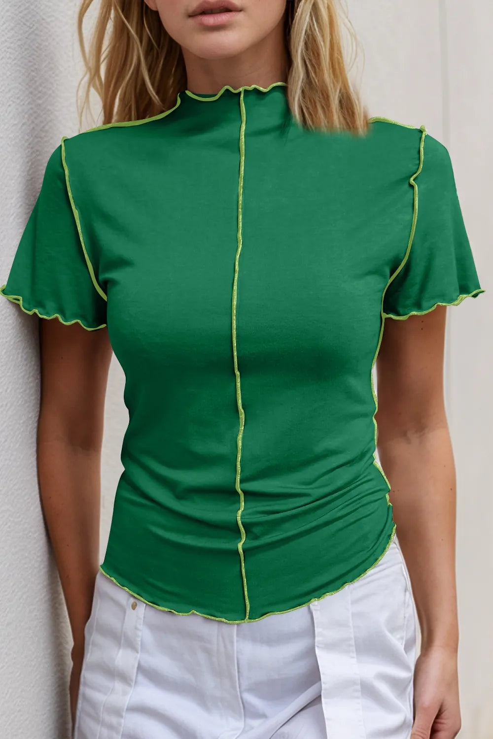 Green top with yellow trim worn by a person against a neutral background