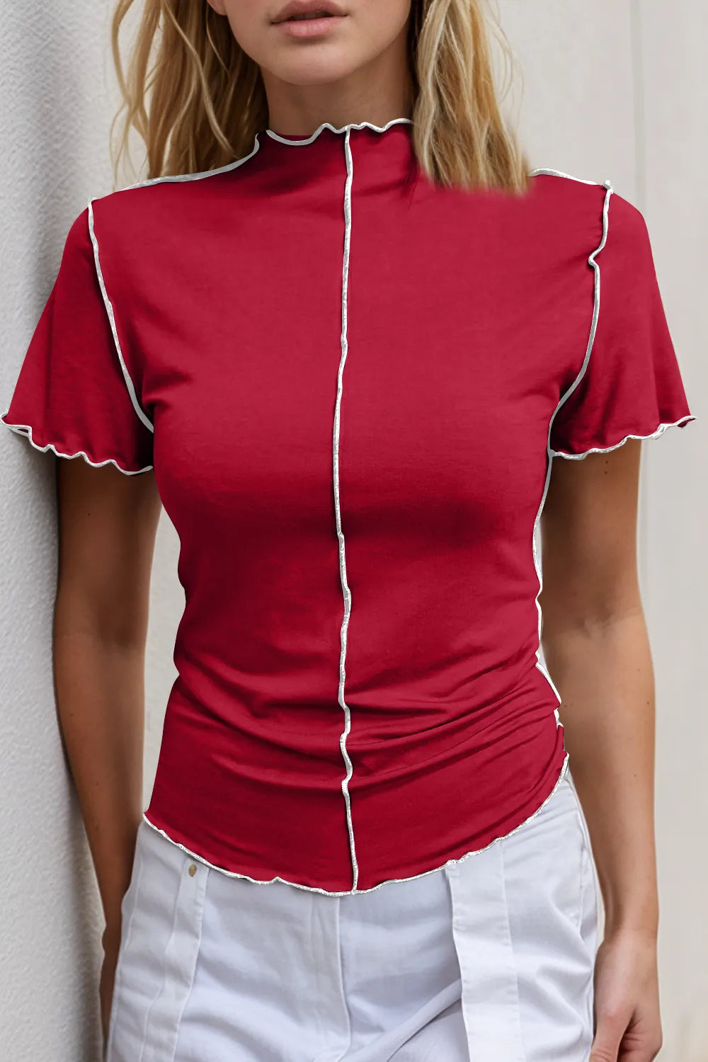 Red short-sleeve top with white trim worn by a person against a neutral background
