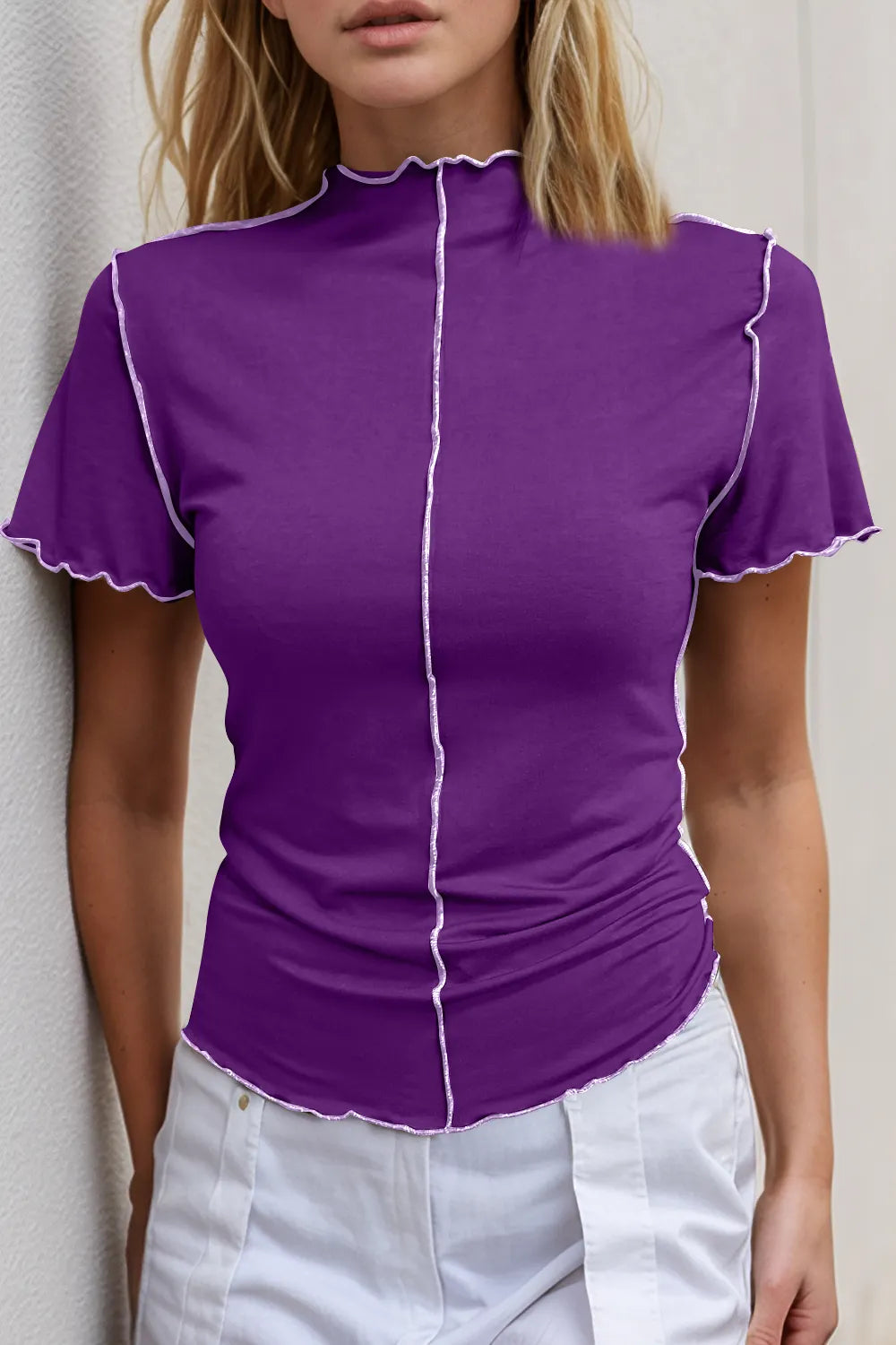 Purple short-sleeve top with white trim worn by a person against a neutral background